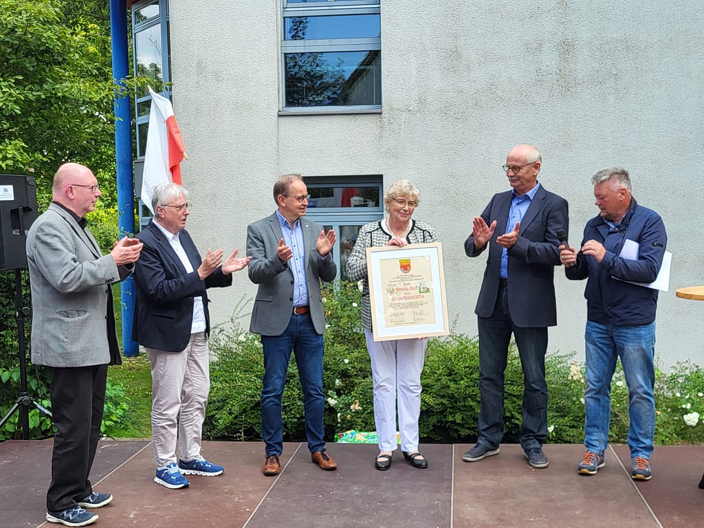 Die Jury um Dr. Michael Hardt (ehem. Pastor in Dahl), Marie-Luise Reineke (Ortsvorsteherin), Antonius Koch (Vorsitzender des Heimat- und Kulturvereins) sowie Jörg Neumann (Ortsheimatpfleger) applaudieren der neuen Preisträgerin. Die Volksbank OWL mit Herrn Grenz (3.v.l.) als Vertreter hat den Geldwert des Preises gestiftet.